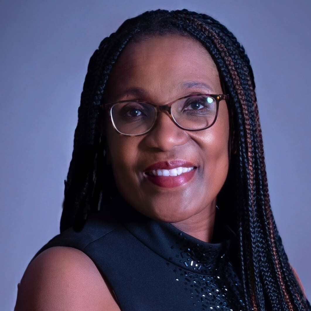 A woman with long braids wearing glasses and a black top.