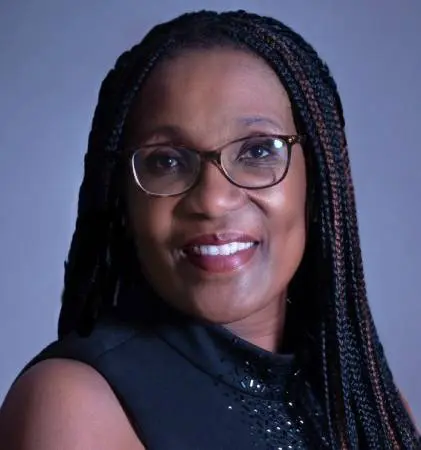 A woman with braids wearing glasses and a black top.