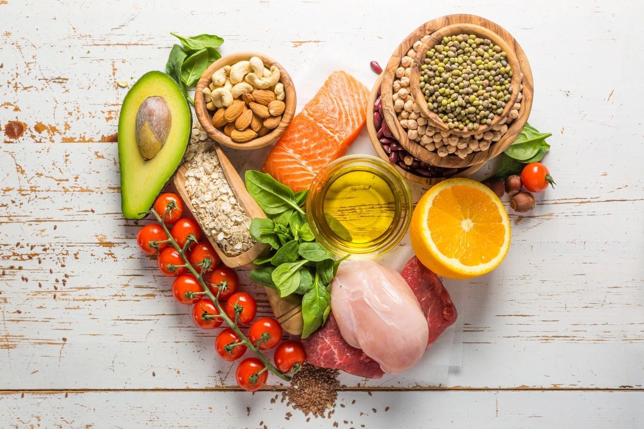 A heart shaped plate of food including meat, vegetables and fruit.
