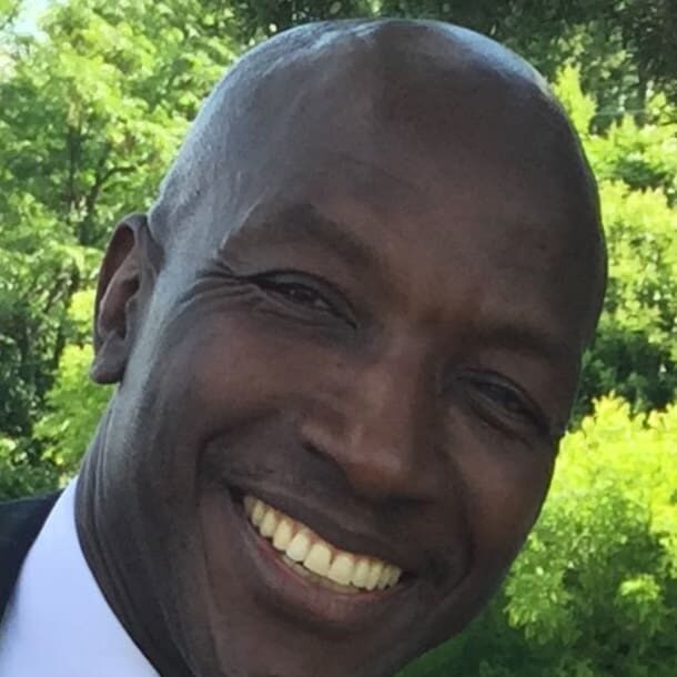 A man smiling for the camera in front of trees.