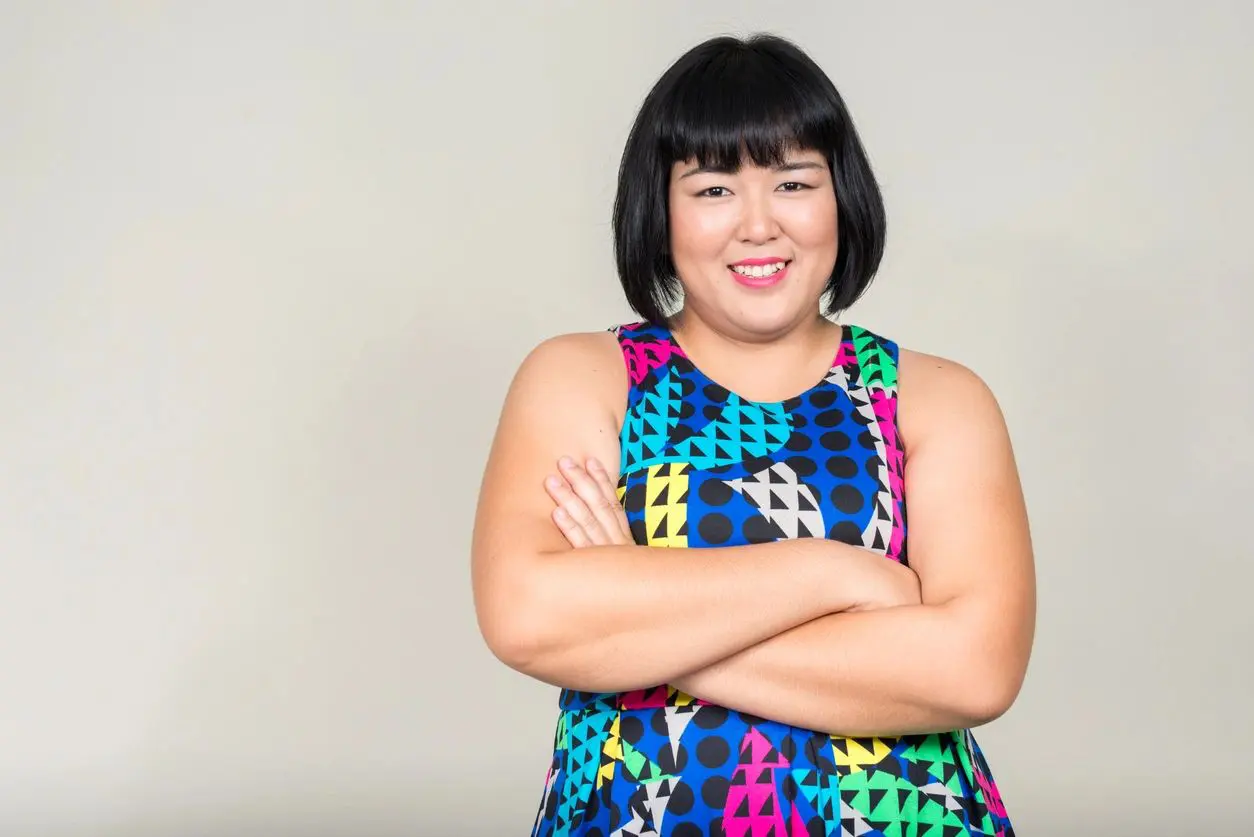 A woman with her arms crossed wearing a colorful dress.