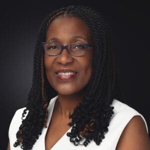 Smiling woman with glasses and braids.