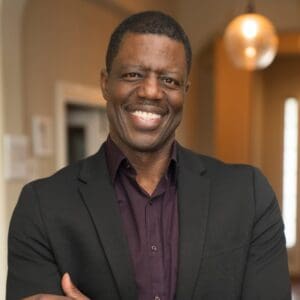 Smiling man in a dark blazer indoors.