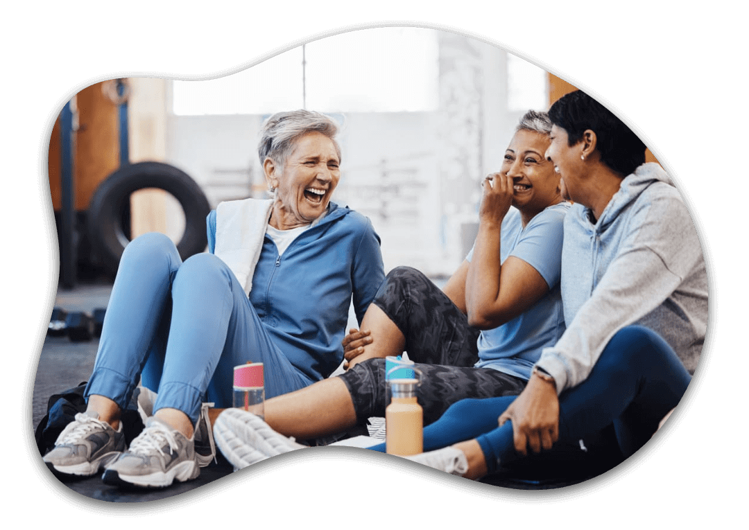 Older women laughing in gym, sitting together.